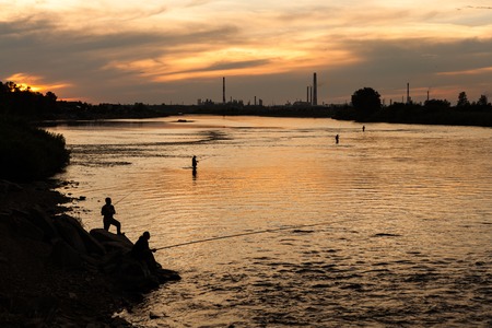 Fishing in unclean water. A big factory spoiled water in the river.の写真素材