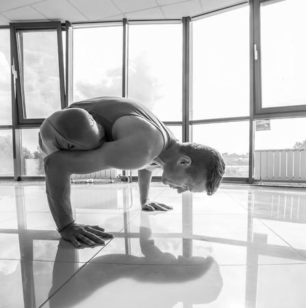 Athletic muscular young man working out, yoga, pilates, fitness training, doing side bend, asana Parighasana, Gate Yoga Pose, gray background, low key shotの写真素材