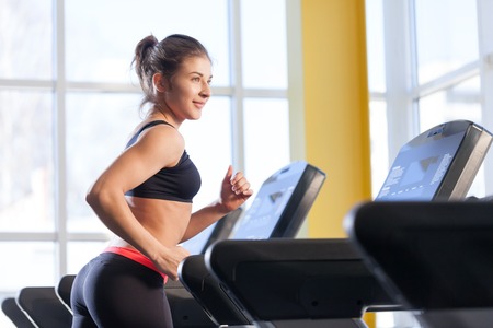 attractive young woman runs on a treadmill, is engaged in fitness sport club
