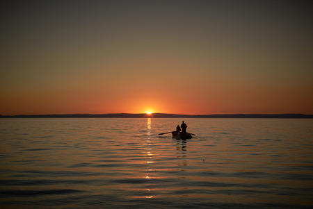 Boat in the sea with two fishermen in it, nets in the sea. Sunset or sunriseの写真素材