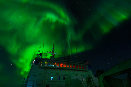 Green northern light, aurora borealis above big boat at nightの写真素材