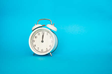 White alarm clock on a blue background. Free space for an inscription. Time conceptの写真素材