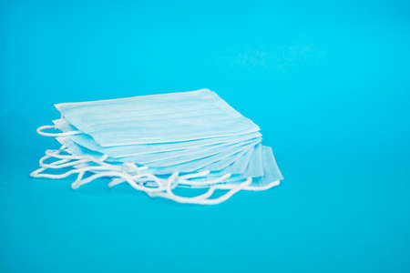 Blue medical face mask isolated on light blue background. A beautiful stack of disposable medical masks on a blue background. Place for textの写真素材