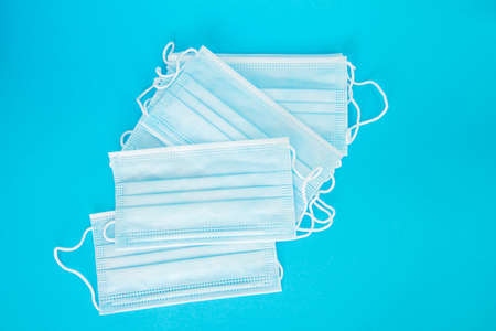 Blue medical face mask isolated on light blue background. A beautiful stack of disposable medical masks on a blue background. Place for textの写真素材