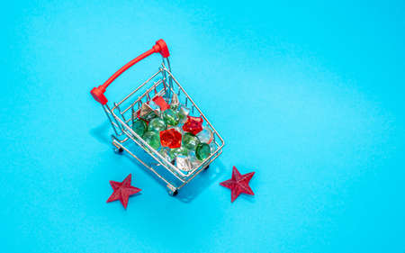 Small cart with a basket for purchases in the store on a blue background. miniature shopping basket...
