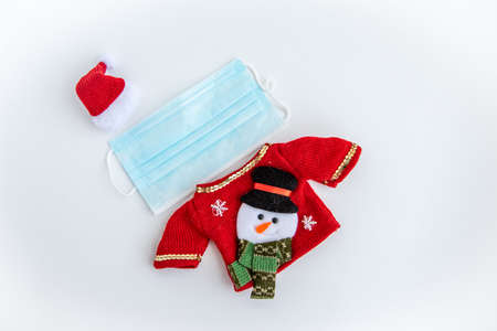 face mask decked out in small holiday Christmas clothes and a cap. Christmas face mask on white backgroundの写真素材