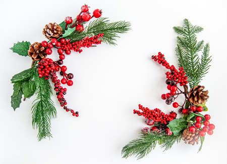 Green fir branches with red berries and Christmas decorations on a white background. Merry Christmas or Happy New Year concept. Flat lay, top view, copy spaceの写真素材