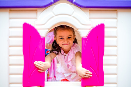 Happy little girl plays in the amusement park. Joyful child on vacation. Portrait of a girl on attractionsの写真素材