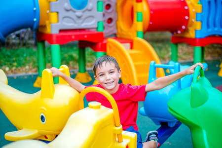 Cheerful boy in a red T-shirt is having fun in an amusement park. Portrait of a happy childの写真素材