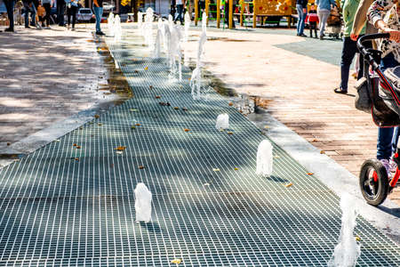 A stream of water splashes on the ground. Jet fountain in the city. Fountain in the city squareの写真素材