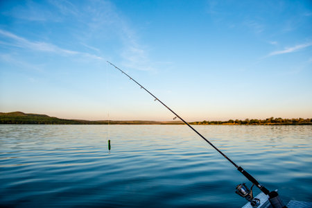 Fishing rod spinning with the line close-up. Fishing rod in rod holder in boat due the fishery day at the sunset. Rod rings. Fishing tackle. Fishing spinning reel.の写真素材