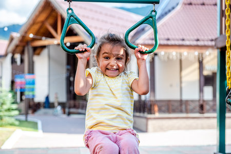 Little girl playing on a swing in the park. Child having fun outdoors.