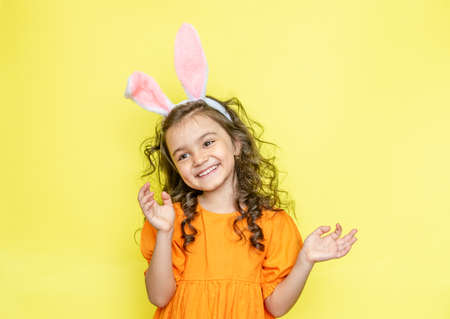 funny happy girl with easter bunny ears on yellow backgroundの写真素材