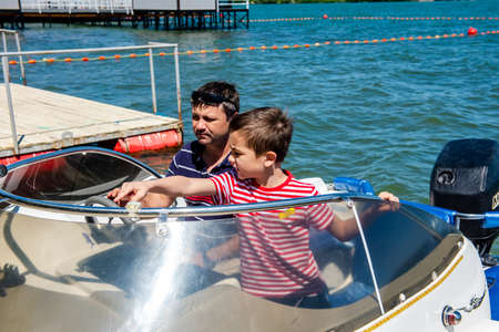 Dad and son are sailing on a motor boat on the lake.の写真素材
