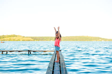 Happy boy and little girl are sitting in a motor boat on the shore of a lake or river. Summer vacation. Rest with children by the water. Brother and sisterの写真素材