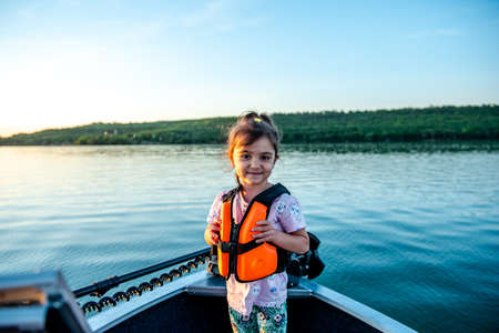 Little happy girl in a life jacket while walking on a boatの写真素材