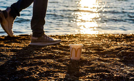 Russia, Gelendzhik - May 4, 2021: white glass of juice from McDonald's. McCafe paper glass drink. A glass of McDonald's by the sea. Paper Cup by the Sea at Sunset The McDonald's logo has branches allのeditorial素材