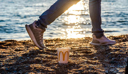 Russia, Gelendzhik - May 4, 2021: white glass of juice from McDonald's. McCafe paper glass drink. A glass of McDonald's by the sea. Paper Cup by the Sea at Sunset The McDonald's logo has branches allのeditorial素材