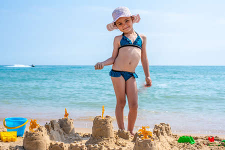 Girl playing on a sandy beach on summer vacation. A child is building a sand castle on the sea.の写真素材