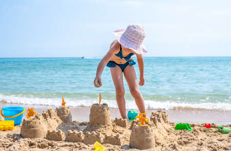 Girl playing on a sandy beach on summer vacation. A child is building a sand castle on the sea.の写真素材
