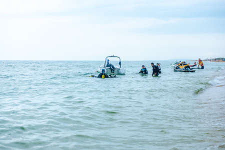 Bugaz Spit. Russia, June 2021. A group of scuba divers in full gear with oxygen cylinders enter the water on the Black Sea coast. Scuba divers are preparing to ride a motor boatのeditorial素材