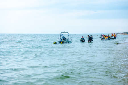 Bugaz Spit. Russia, June 2021. A group of scuba divers in full gear with oxygen cylinders enter the water on the Black Sea coast. Scuba divers are preparing to ride a motor boatのeditorial素材