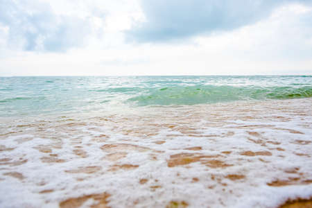 storm on a sandy beach during the day. dramatic ocean scenery with cloudy sky. stormy water and crashing waves in daylightの写真素材