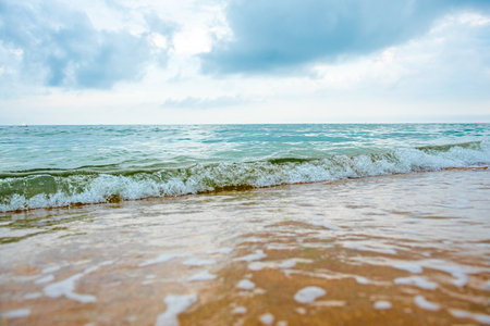 storm on a sandy beach during the day. dramatic ocean scenery with cloudy sky. stormy water and crashing waves in daylightの写真素材