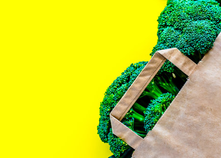 Eco bag with groceries on a yellow background. Juicy greens and broccoliの写真素材