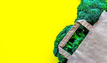 Eco bag with groceries on a yellow background. Juicy greens and broccoliの写真素材