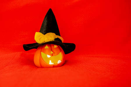 A creepy grinning Halloween pumpkin glows on a red background. Jack-o-lantern in a witch hat on a red background. Place for advertising.の写真素材