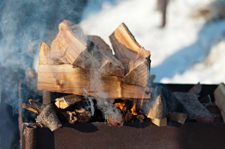 inflames smoking logs in the grill outdoors