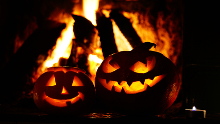 Creepy halloween pumpkins near a fireplace. Fire on the background.の写真素材