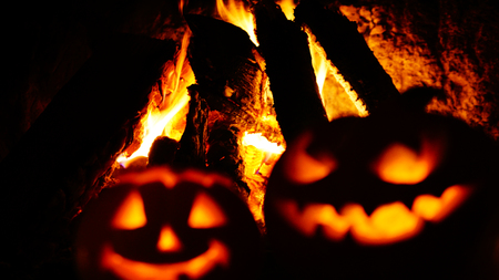 Creepy halloween pumpkins near a fireplace. Fire on the background.の写真素材