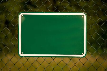 Fence with a blank green signの写真素材