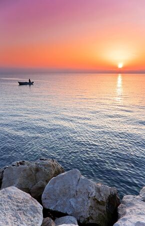 Man in a boat angling at sunsetの写真素材
