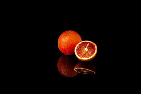orange on shiny black background with reflectionの写真素材