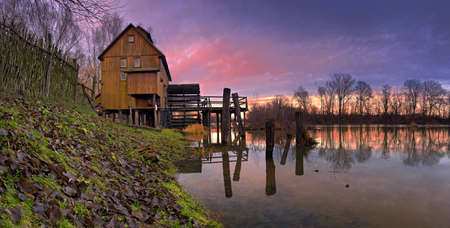 The sunrise over the old wooden watermill の写真素材