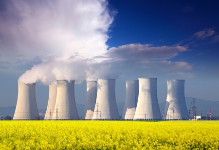 Nuclear power plant with yellow field and big blue clouds Nuclear power plant with yellow field and big blue clouds