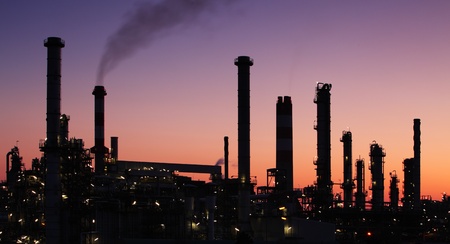 Oil refinery factory silhouette over sunset