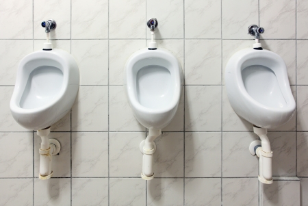 line of white porcelain urinals in public toiletsの写真素材