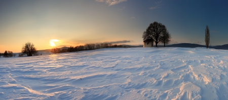 Sunset on frozen field with a chapel.の写真素材