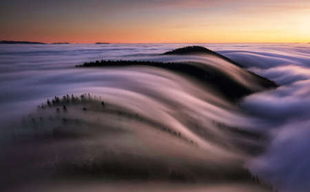 Beautiful sunset on the hill above clouds