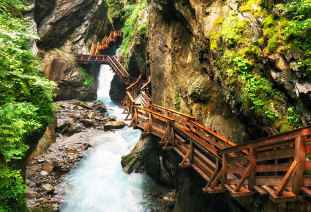Wooden hike trail path inside a gorge with bue mountain river, Sigmund Thun Klamm, Kaprun, Austriaの写真素材