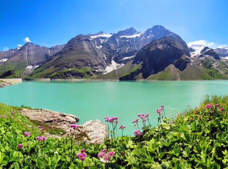Kaprun water reservoirs, Kaprun dam, Austria. Stunning turquoise picturesque lake, Alpine reservoir, surrounded by the green Alps mountains, blue sky, and clouds. Artificial power station, top view.の写真素材