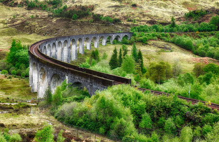 Glenfinnan Viaduct, Scotland. Travel tourist destination in Europe. Old historical steam train riding on famous viaduct bridge. Highlands, mountains, outdoor background.の写真素材