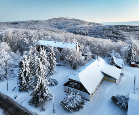 Aerial view of village in snow, road, forest at winter. Top view from drone of mountain village, snowy pine trees at sunrise.の写真素材