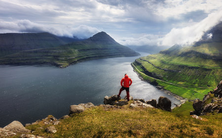 Tourist in a red jacket explores natural attractions. Summer mountain landscape
View on Funningur fjord from the Funningur top. Eysturoy Island, Faroe islands.の写真素材