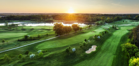 Golf course at sunset with beautiful sky and sand trap. Scenic panoramic view of golf fairway with bunker from droneの写真素材