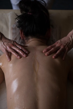Ayurveda Massage concept. Beautiful young woman reciving relxing Massage of Her Back from Professional Masseurの写真素材